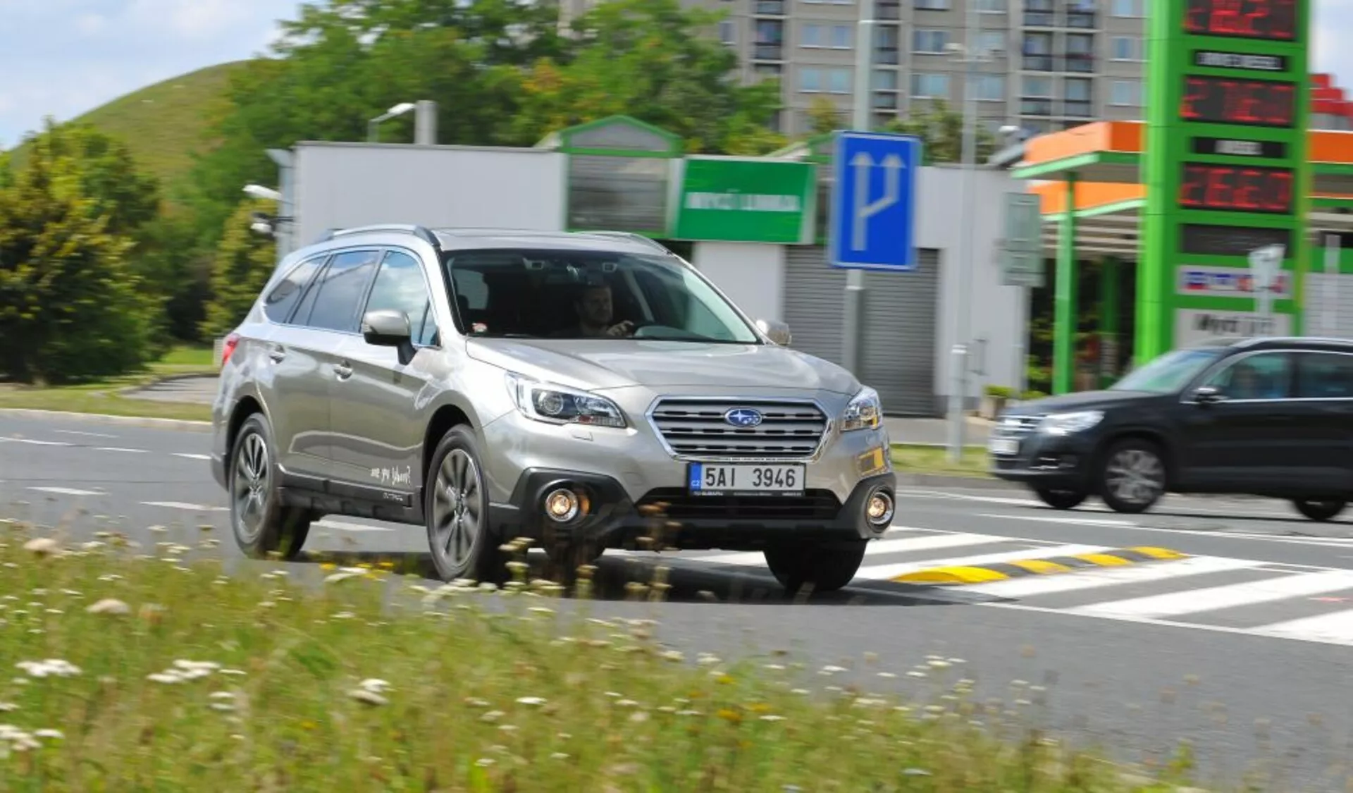 Subaru Outback från 2003 i rörelse, som visar en tre kvarts framsida med detaljerad grill, strålkastare och hjul, vilket framhäver dess kompakta SUV-design och användbara funktioner som takräcken, i soliga förhållanden.