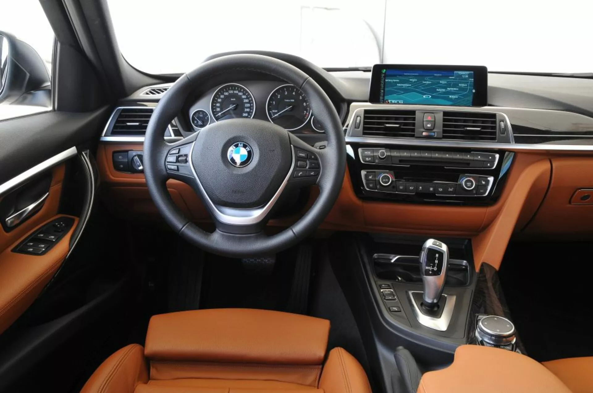 Frontvy av interiören i BMW Outback 2003 som visar förarens område och mittkonsol med monterade kontroller på ratten, analoga urtavlor och en central digital display på instrumentbrädan, bredskärms infotainmentsystem och läderklädda säten