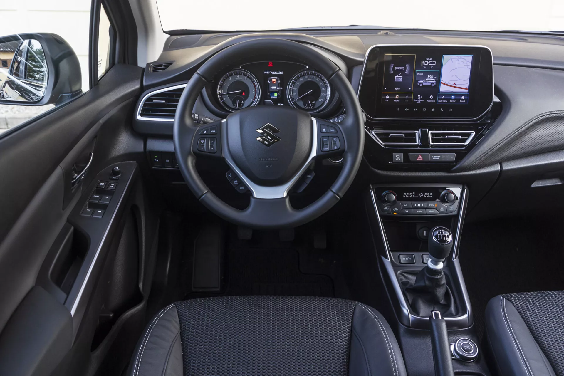2022 Suzuki S-Cross främre kupéinteriör som visar instrumentbräda, ratt med monterade kontroller, digital-analog instrumentkluster, pekskärmsunderhållningssystem, klimatkontrollrattar, läder växelspak, körningslägesväljare, elektronisk parkeringsbroms och dörrpanel med strömkontrollknappar