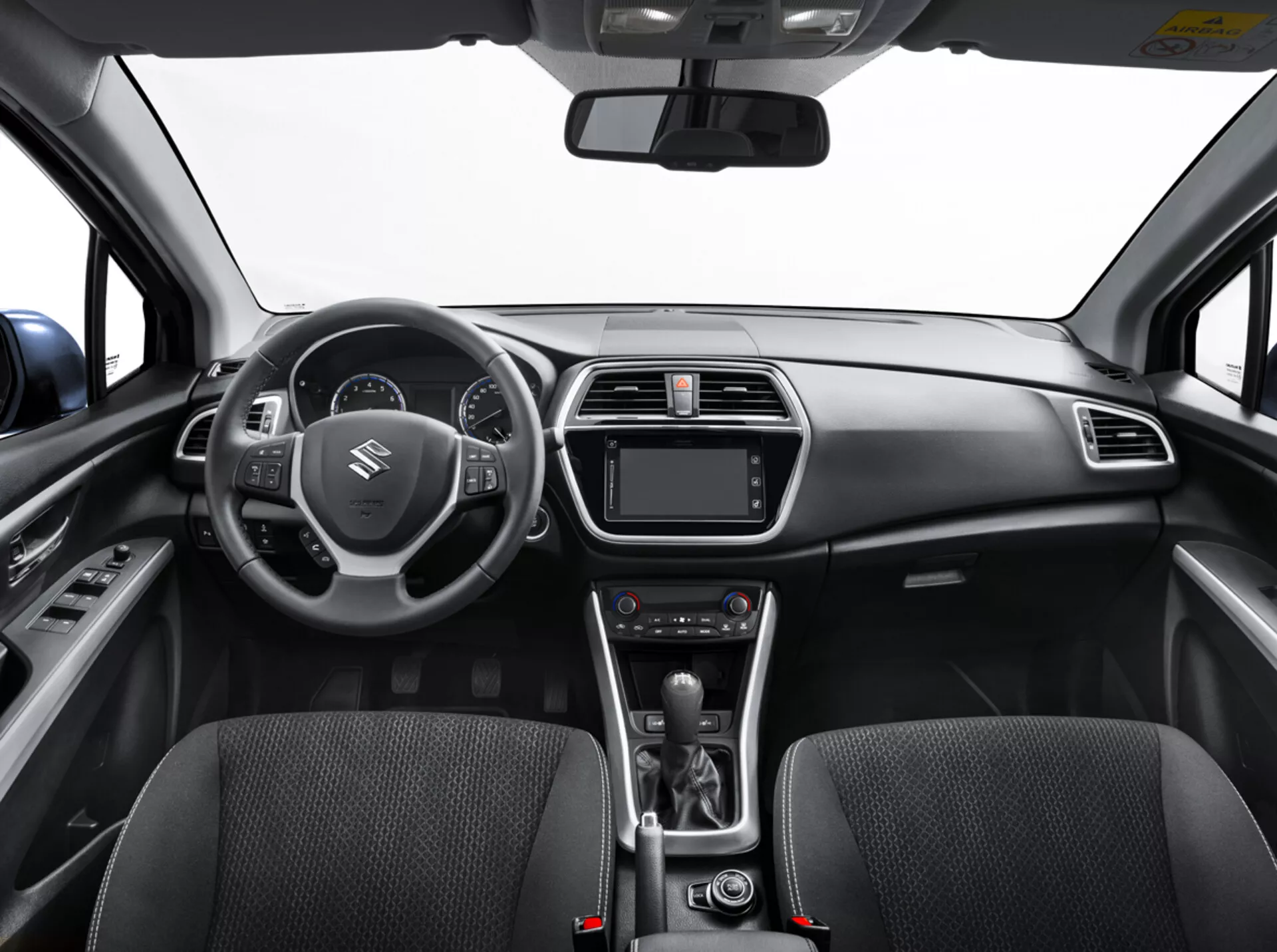 Interiörvy av Suzuki S-Cross 2022 från baksätet som visar instrumentbrädan, ratten med kontroller, digital instrumentkluster, infotainmentsystem, klimatkontroller, automatisk växelspak och detaljerade framsäten med tygtextur