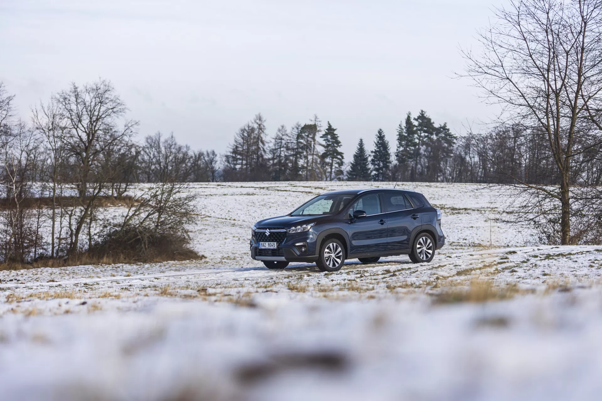 Suzuki S-Cross 2022 i ett vinterlandskap med snö, som visar upp sin dynamiska design, avancerad belysning, legeringshjul och takräcken, betonande sin SUV-stil och terrängkörningsförmåga.