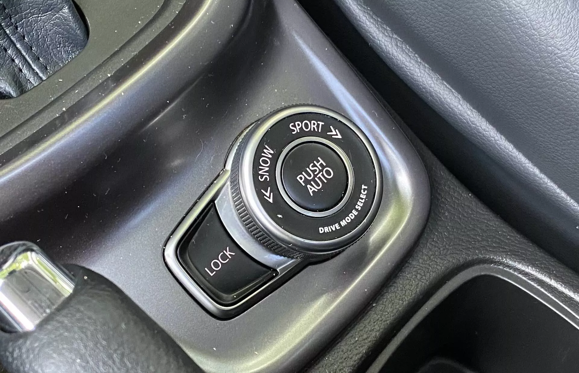 Närbild av körlägesväljaren i mittenkonsolen på en Suzuki Vitara 2018 med etiketter för SNOW, SPORT, LOCK och AUTO-läge, texturerad omkrets och borstade metalliska detaljer.