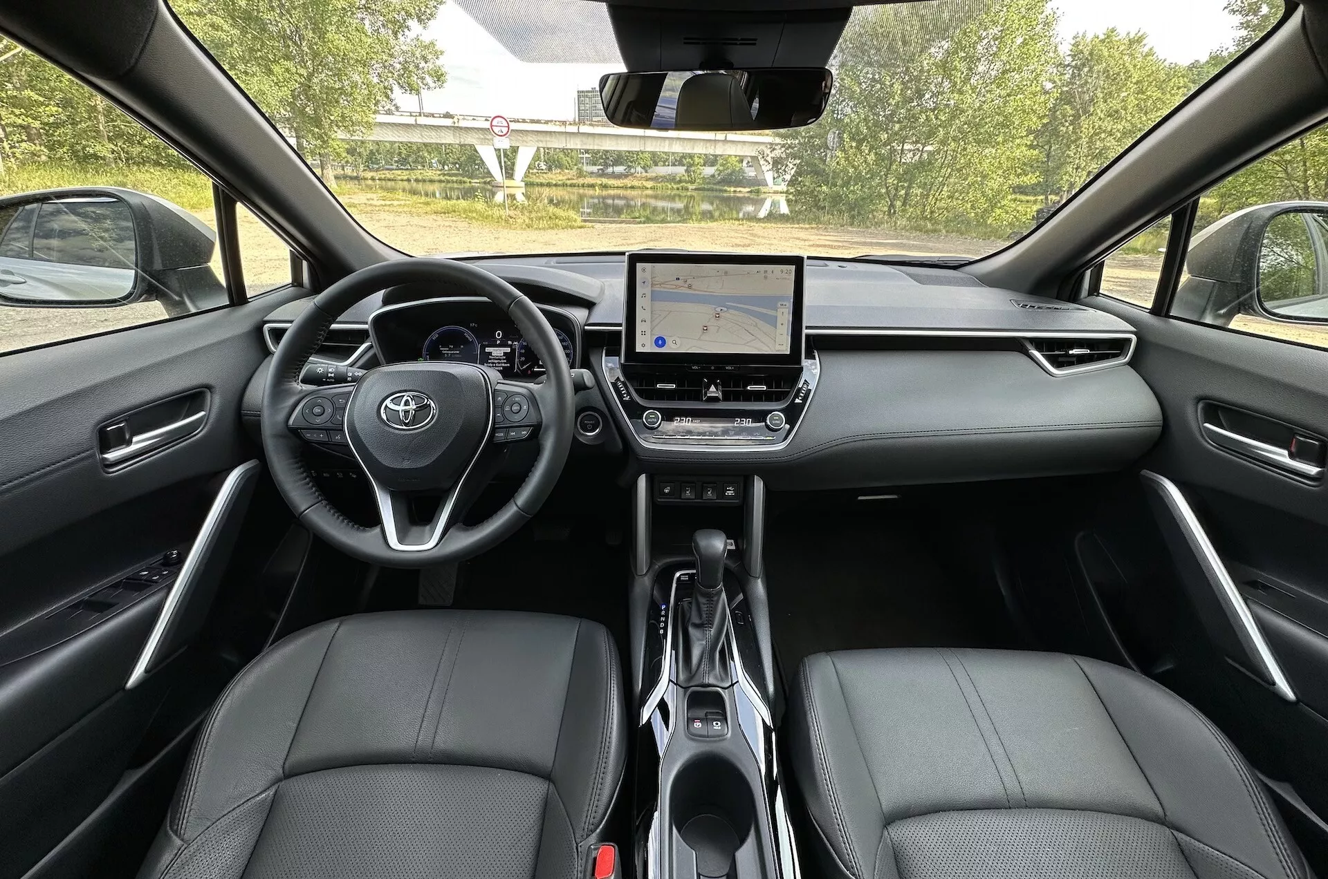 Interiörvy av Toyota Corolla Cross 2022 från baksätet som visar instrumentbrädan, pekskärmsinfotainmentsystem och framsäten i läder