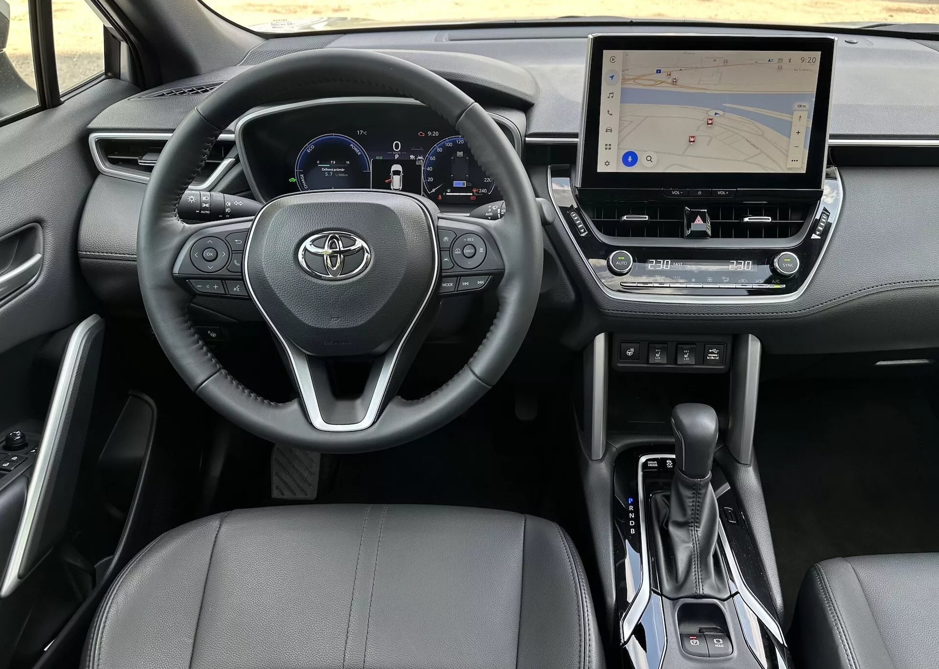 Interiör av Toyota Corolla Cross 2022 från förarens perspektiv som visar ratten, instrumentklustret, mittkonsolen och passagerarsätet
