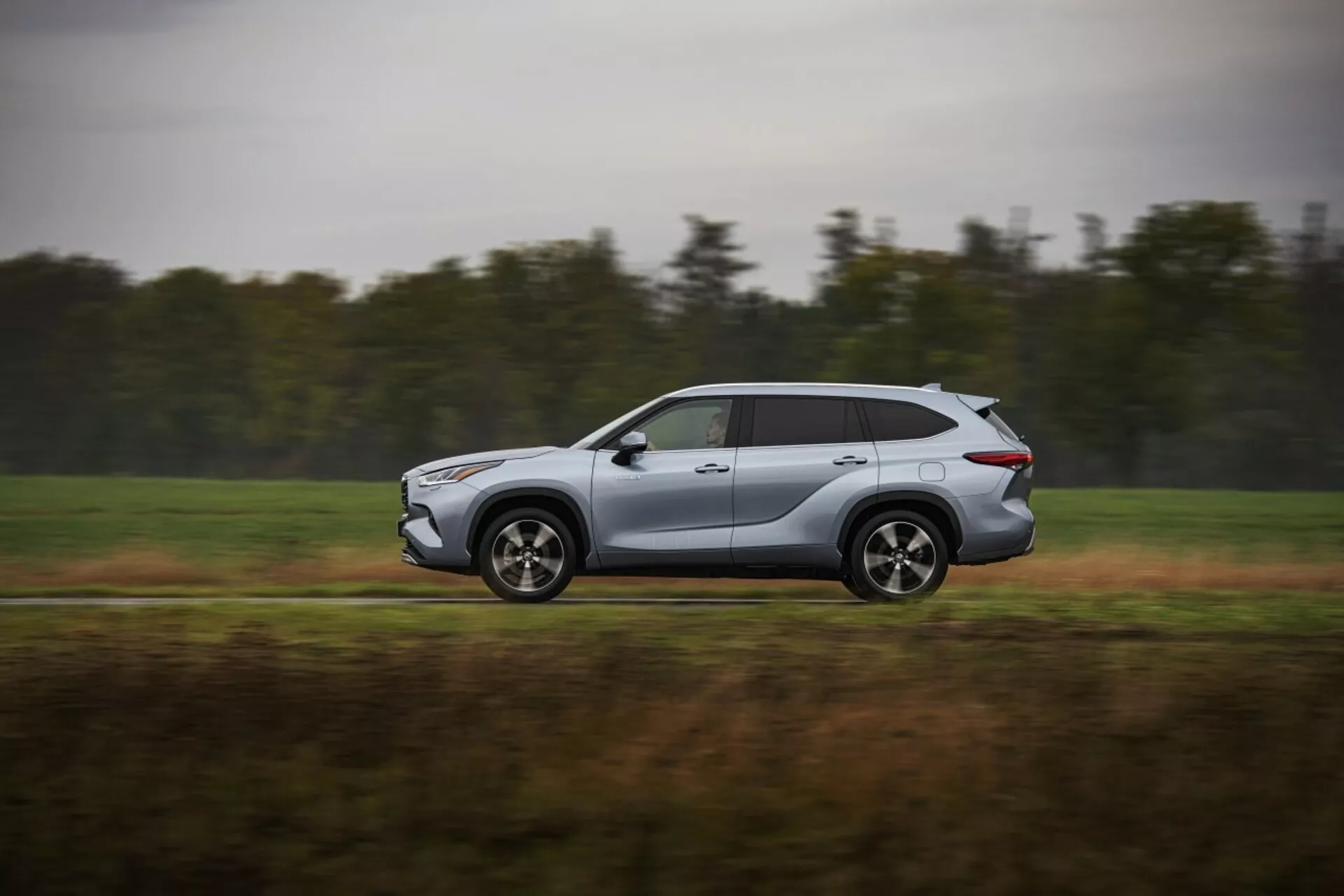 Toyota Highlander 2021 i rörelse, modern silver SUV fångad från en sidoprofil, som visar aerodynamisk design och tekniska funktioner