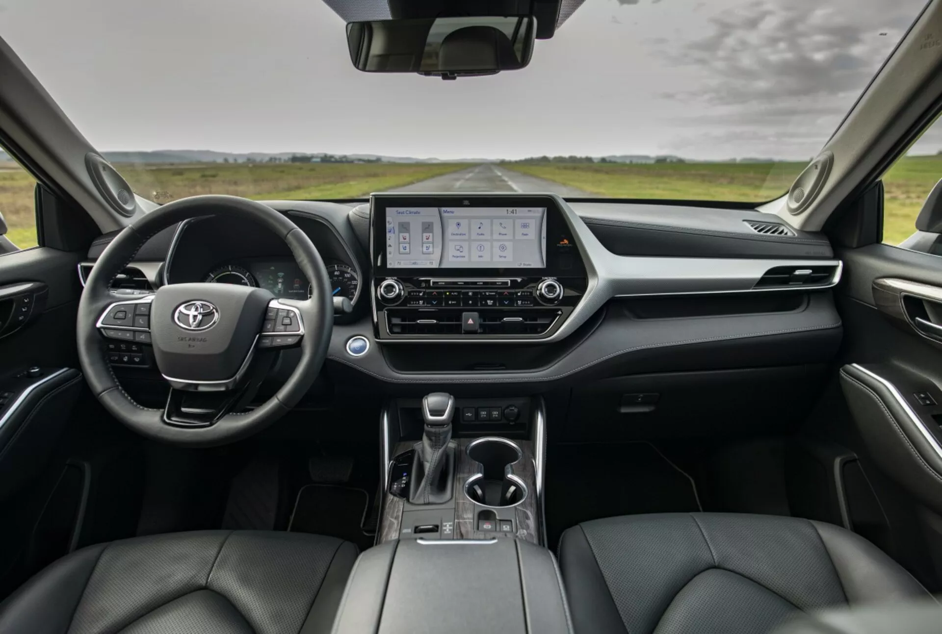 Översikt över interiören i Toyota Highlander 2021 som visar instrumentbrädan, digital instrumentkluster, infotainmentskärm och framstolar klädda i läder från bakre sittplatsernas perspektiv