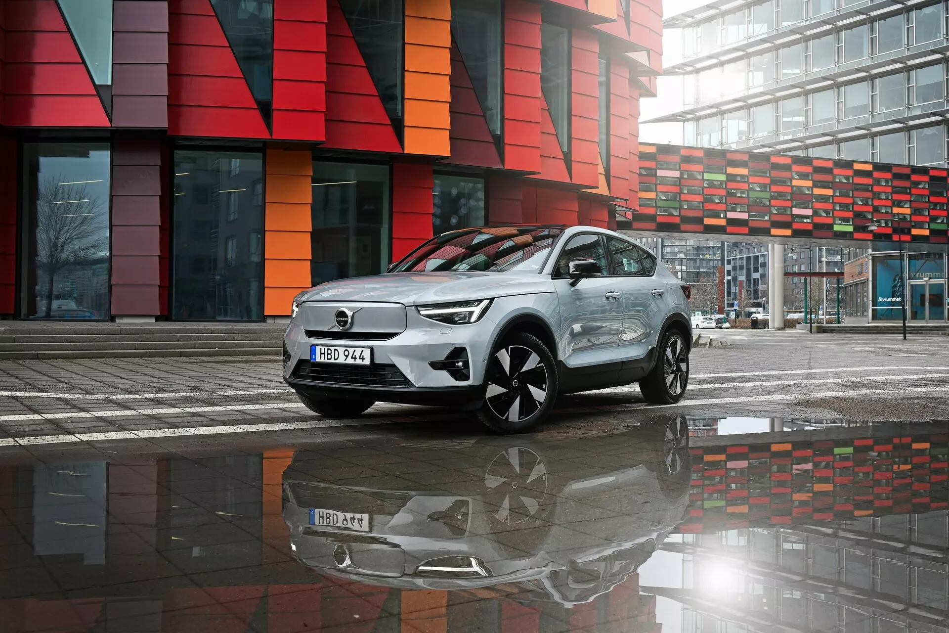 2024 Volvo EC40 1:a generationens elektriska crossover SUV som visar avancerad aerodynamisk design och LED-belysningsteknologi, parkerad på vått underlag med tydlig reflektion, betonar miljövänliga egenskaper och stadsinriktad livsstil