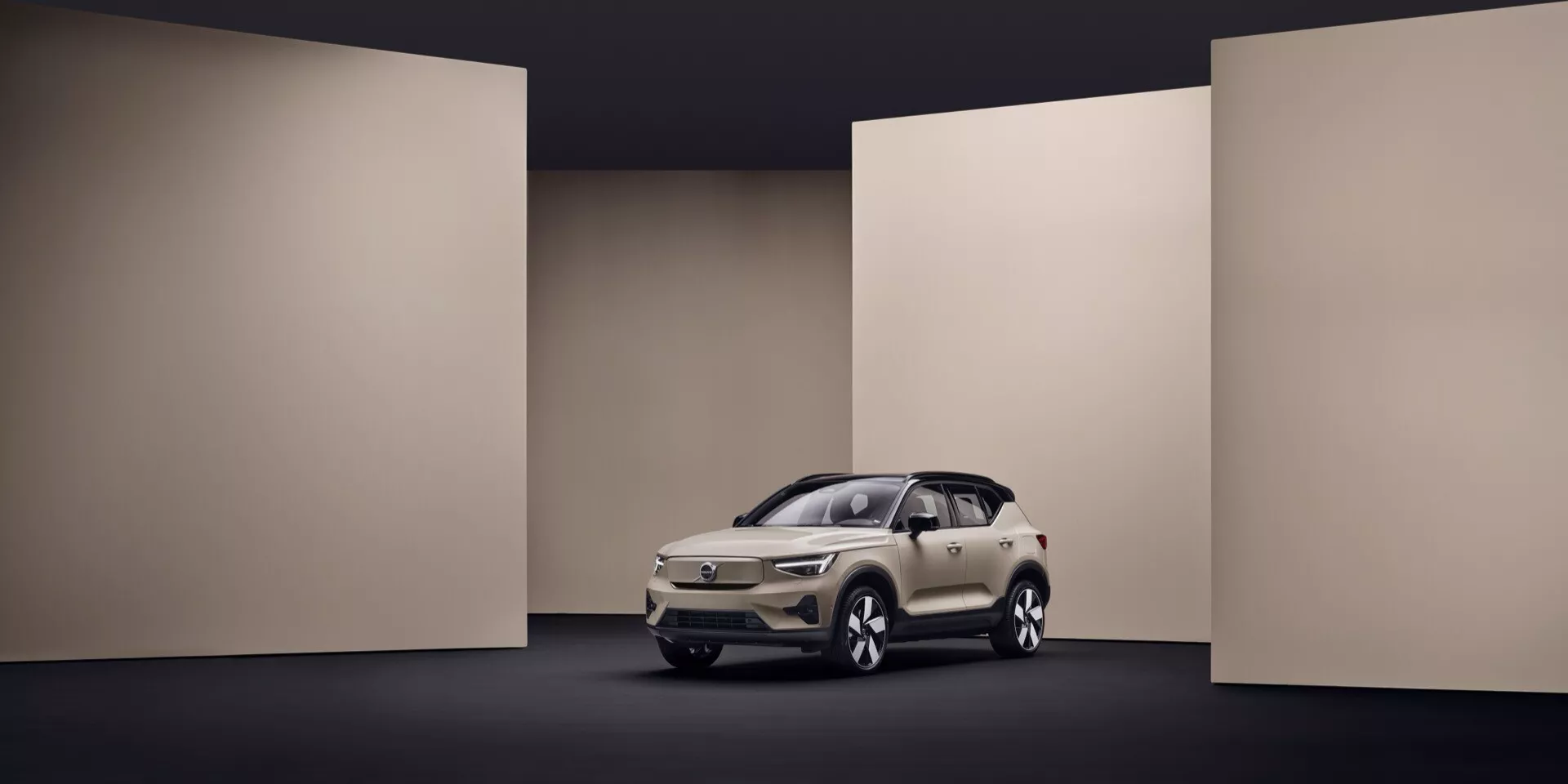 2024 Volvo EX40 1:a generationen i krämfärg som visas i en studio med kontrollerad belysning, framhäver dess smakfulla design, LED-strålkastare, distinkt grill och moderna teknikfunktioner