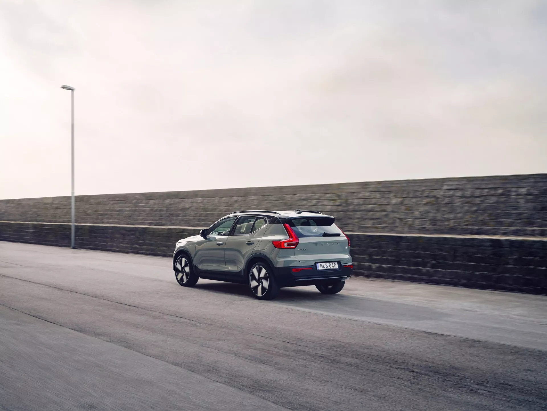 2024 Volvo EX40 kompakt SUV i rörelse, med LED bakljusdesign, bakspoiler för aerodynamik och tillverkares märke, fångad i skymningen med rörelseoskärpa för en dynamisk effekt
