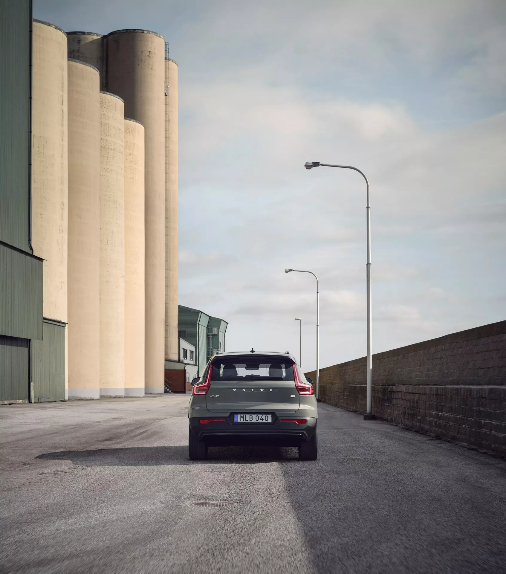 Bakvy av Volvo EX40 1:a generationen 2024 på asfaltväg, modern hatchback med bakruteviskare, hajfenaantenn, spoiler, samtida bakljus, parkeringssensorer och dubbla avgassystem