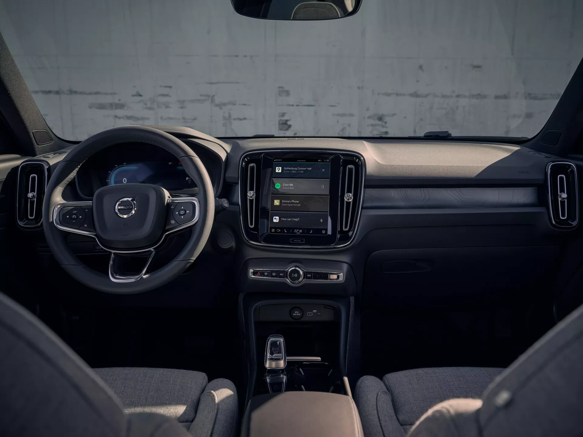 Interiörvy av Volvo EX40 2024 som framhäver instrumentbrädan, mittkonsolen och ratten från baksätespassagerarens perspektiv, visar modern design och teknologiska funktioner