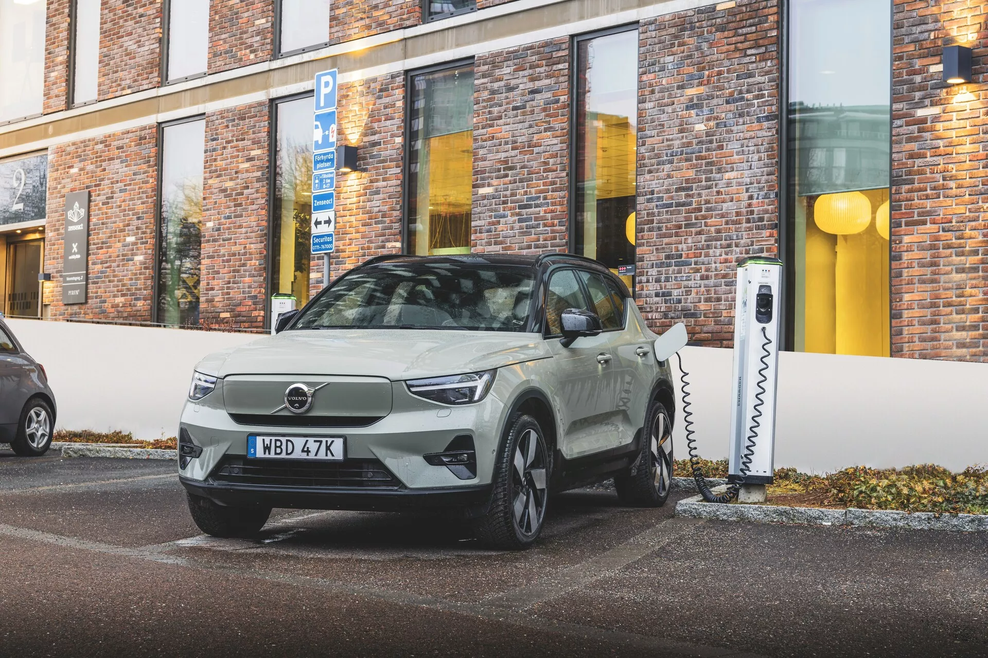 2024 Volvo EX40 1:a generationens elbil parkerad i en vinkel, som visar upp en elegant design och tekniska funktioner som LED-ljus och laddningsport, i en stadsmiljö