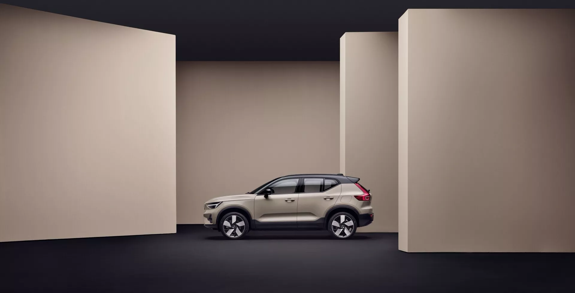 Volvo EX40 1:a generationen 2024 visas i fullprofil mot en mörktonad bakgrund, framhäver fordonets sidodesignelement, aerodynamiska karosseri och avancerade funktioner som lätta legeringshjul och integrerade blinkers