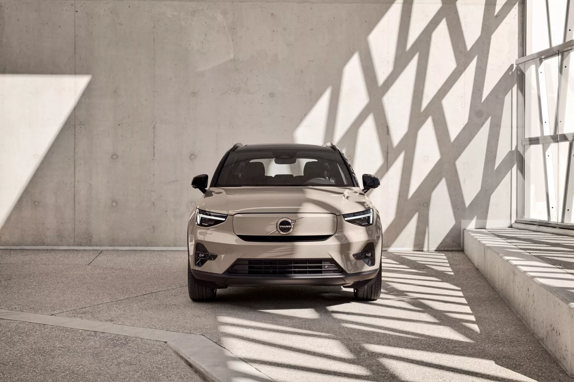 Volvo EX40 2024, 1:a generationen, visas från en främre vänster skev perspektiv i en inomhusutställningslokal med neutral ton, LED-strålkastare och en modern, aerodynamisk design med uppenbara elektriska fordonsegenskaper