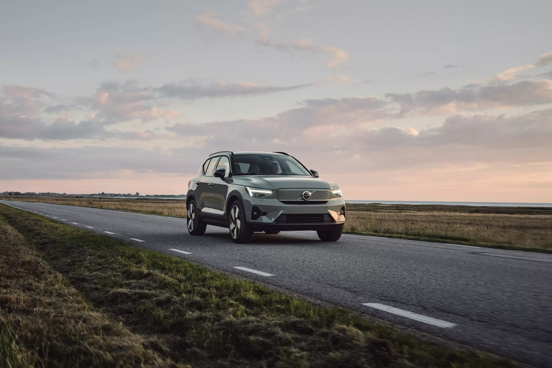 Volvo EX40 2024 1:a generationen i en dynamisk tredjedels framsida, visar LED-strålkastare, distinkt grill, legeringshjul och modern SUV-design i metallisk färg under mjukt naturligt ljus