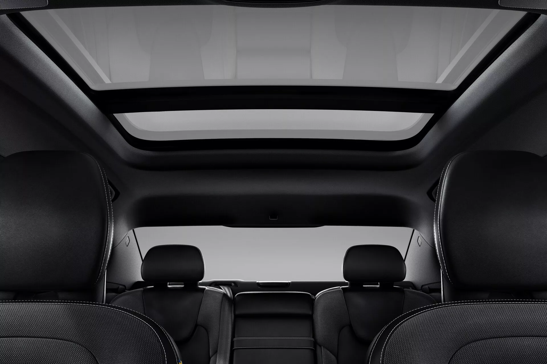 Interiörvy av en Volvo S60-V60 2018 (3:e generationen) från bakre perspektivet, med fokus på det stora panoramasoltaket med en infällbar täckning och premium svarta lädersäten med integrerade nackstöd.