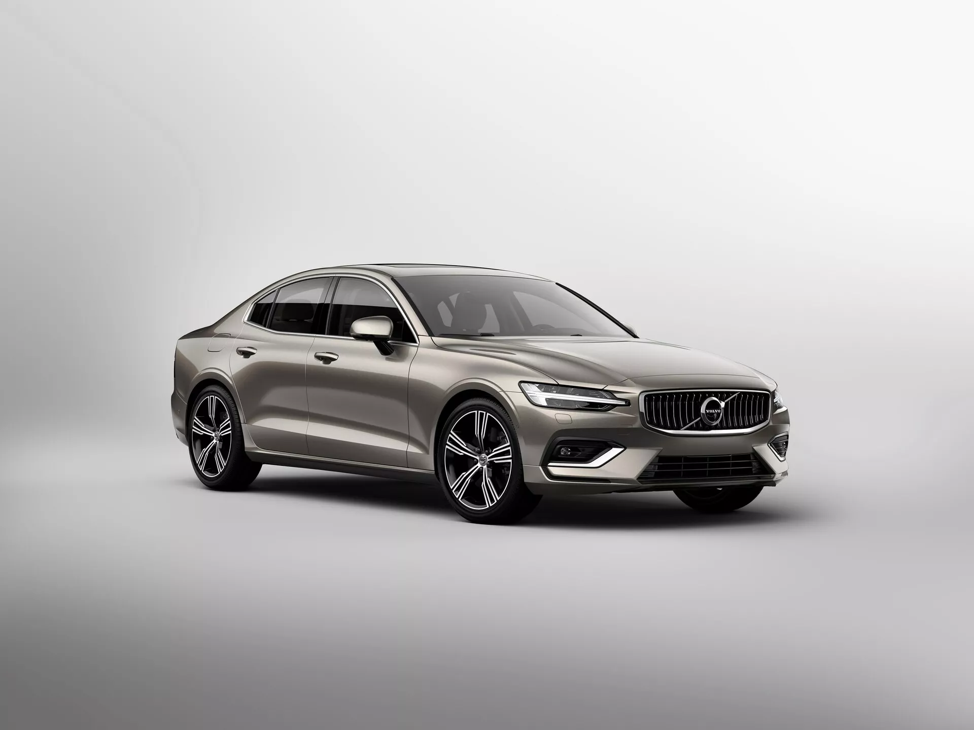 Främre trekvartsvy av en Volvo S60/V60 2018 sedan. Visar LED-dagljus, LED-strålkastare, flerspoked fälgar, vertikal-lamellfrontgaller med emblem, komplexa karosslinjer, metallisk finish och sidospeglar i karossens färg med möjliga indikatorer. Neutral bakgrund för fokuserad presentation.