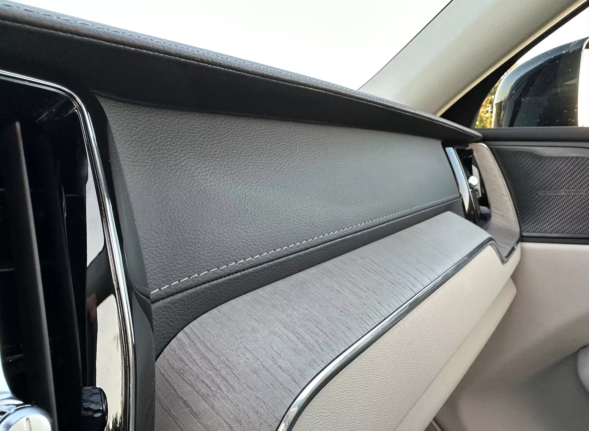 Närbild av dörrpanelen inuti Volvo XC60 2021 Recharge Plug-In Hybrid, med fokus på de lyxiga materialen och designelementen från en passagerares perspektiv.