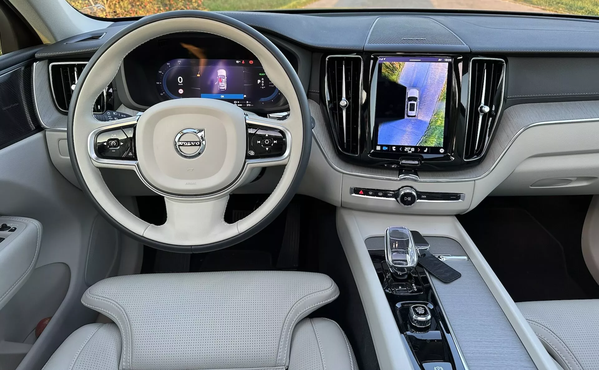 Interiörvy av Volvo XC60 Recharge Plug-in Hybrid 2021 från baksätet, som visar instrumentbrädan, digitala skärmar, multifunktionsratten och mittkonsolen
