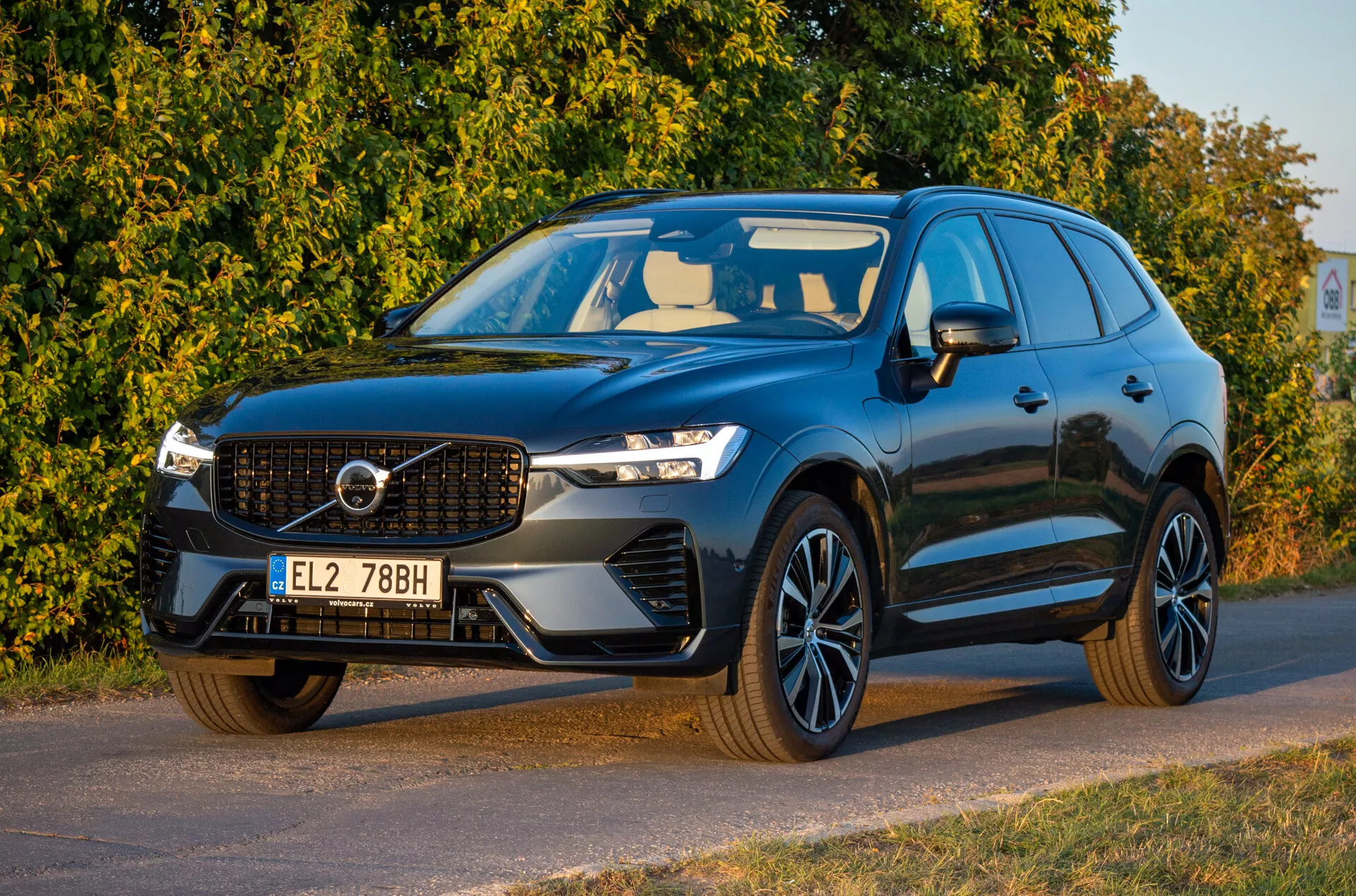 Volvo XC60 Recharge plug-in hybrid från 2021 i mörk färg, framifrån tre kvarts vy som visar LED-strålkastare, emblematisk grill, sportiga legeringshjul och aerodynamisk design, parkerad diagonalt vänd mot vänster med en detaljerad titt på framsidan och förarsidan.