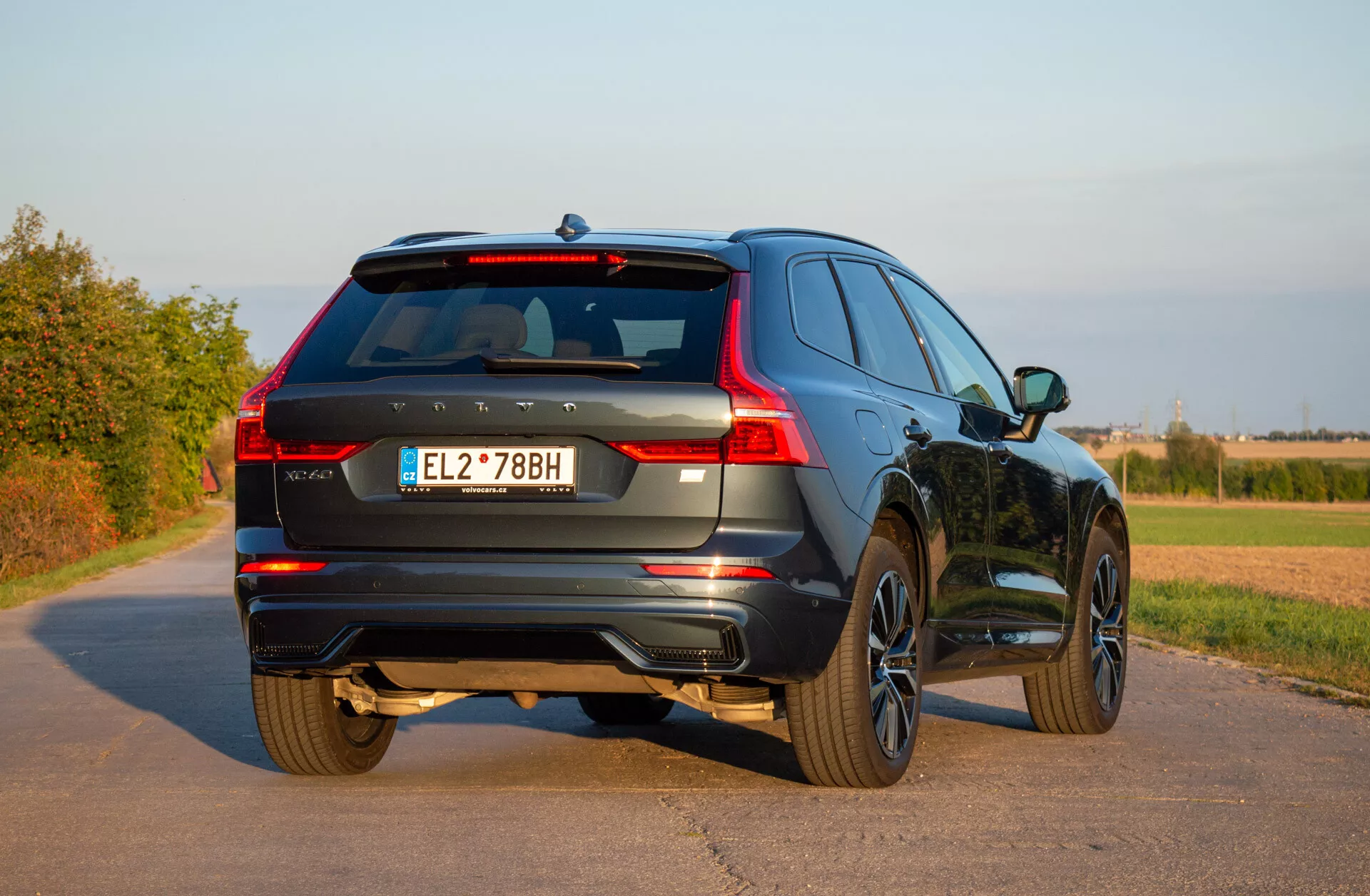 2021 Volvo XC60 Recharge plug-in hybrid SUV parkerad på en asfalterad väg som visar sin bakre tredjedels vy, med LED-bakljus, legeringshjul och dynamisk design i en landsbygdsmiljö under klar himmel