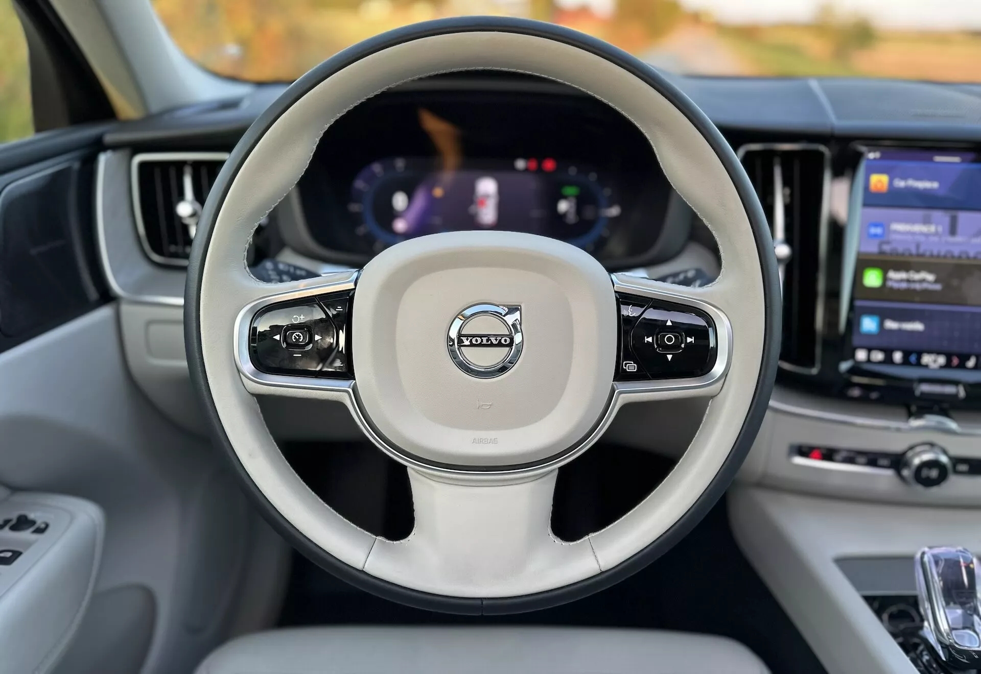 Interiörvy av en 2021 Volvo XC60 Recharge Plug-In Hybrid från förarsätet som visar ratten med monterade kontroller, en digital instrumentpanel och ett stort pekskärms-underhållningssystem