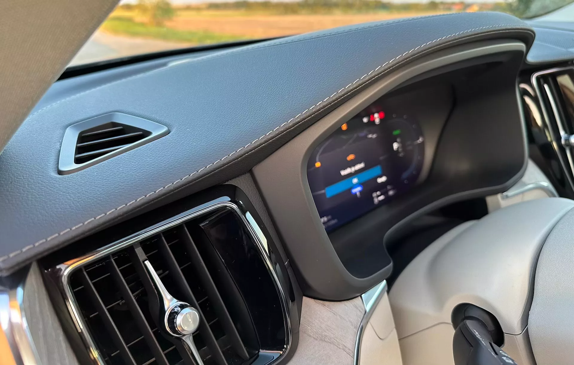 Interiörvy av en Volvo XC60 Recharge Plug-In Hybrid 2021, som visar instrumentbrädan med fokus på den avancerade digitala instrumentklustern och material av hög kvalitet, från perspektivet av främre passagerarsätet.