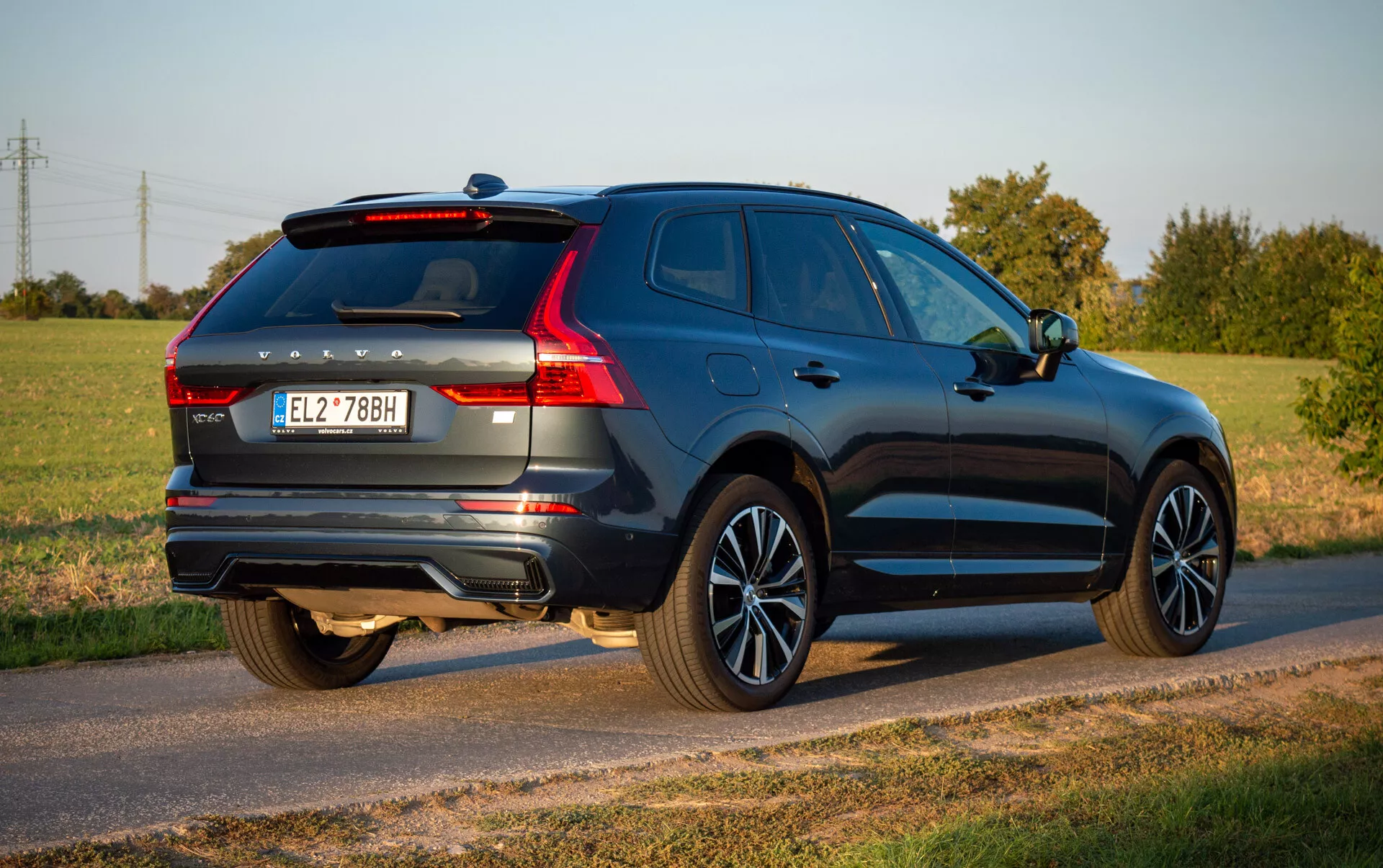 Volvo XC60 Recharge Plug-In Hybrid 2021 i djupblå, visar upp sin aerodynamiska design och moderna funktioner såsom LED-baklampor, lättmetallfälgar och dubbelt avgassystem parkerad på en landsväg under klar himmel