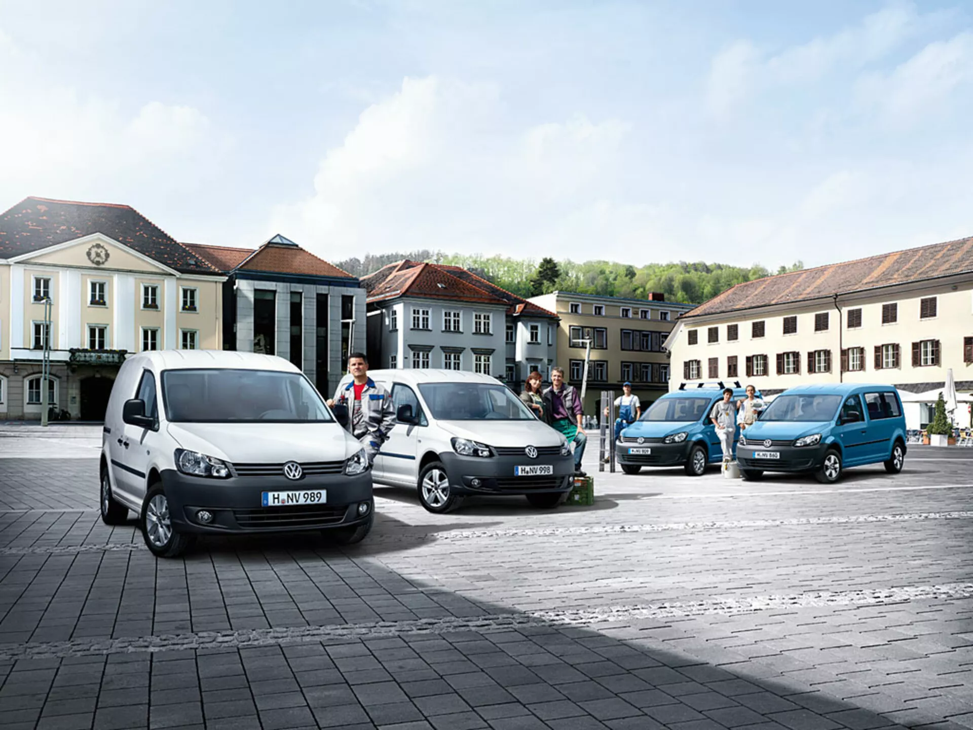 Volkswagen Caddy 2010 flerändamålsbussar parkerade i diagonala linjer på kullerstensplats, visar olika färger och vinklar, med distinkta främre och sidoprofiler synliga