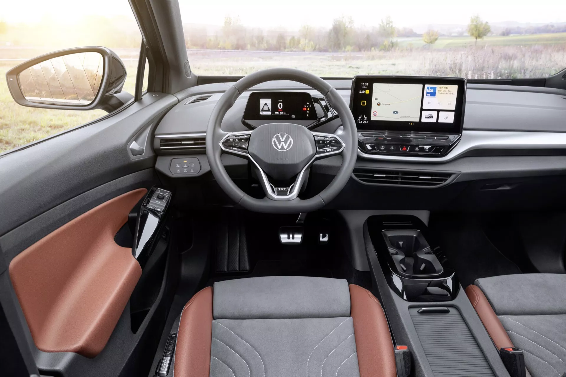 Volkswagen ID4 2020 interiör från förarperspektiv som visar läderomslaget ratt med platt botten med kontroller, digital instrumentpanel, widescreen-infotainmentskärm, minimala fysiska kontroller, modern växelväljare och detaljer på förarsidan dörr inklusive sidospegel och lyxiga två-ton säten.