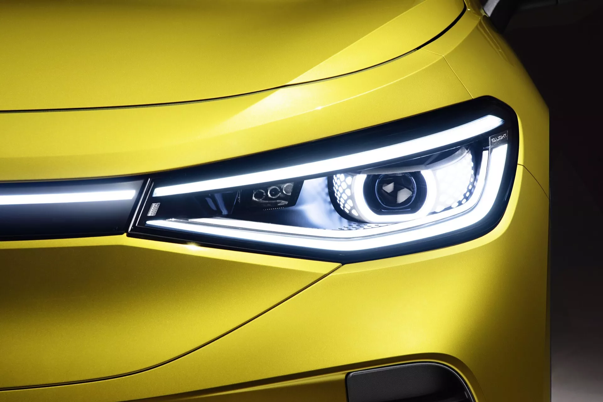 Närbild av strålkastaren på en VW ID.4 1:a generationen 2020, som visar den eleganta LED-dagsljusdesignen, vinkel estetik och livfullt gula yttre