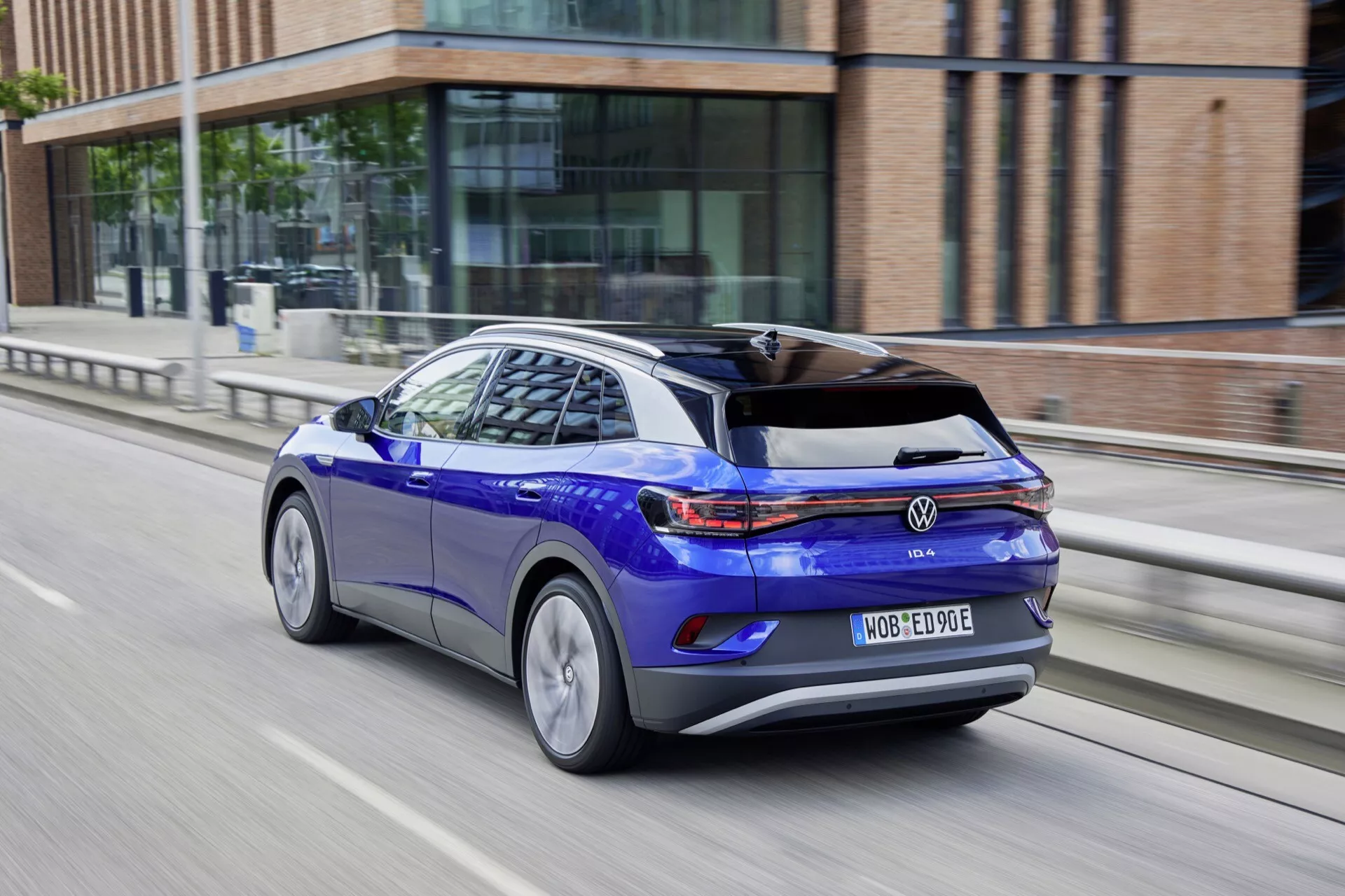 Volkswagen ID.4 1:a Generationen 2020 i Glänsande Blått, Bakifrån Tre-Kvarts Vy i Rörelse med Aerodynamisk Silhuett, LED Bakljus, Legeringshjul och Egenskaper för Elbil