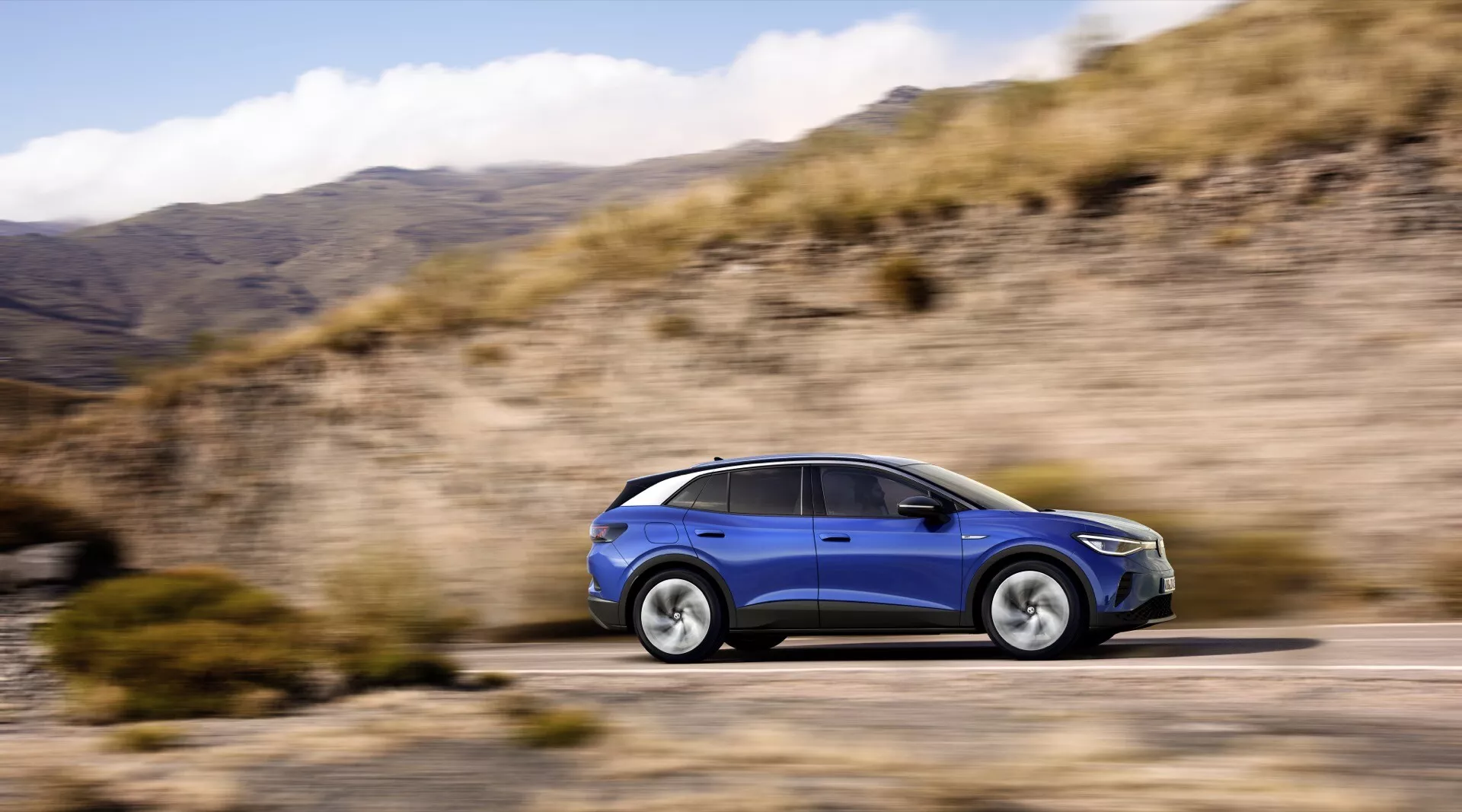 2020 Volkswagen ID.4 1:a generationen i dynamisk sidovy som visar avancerade tekniska funktioner, LED-strålkastare och aerodynamisk design mot en suddig naturlandskapsbakgrund, som framhäver dess förmåga att hantera olika terränger.