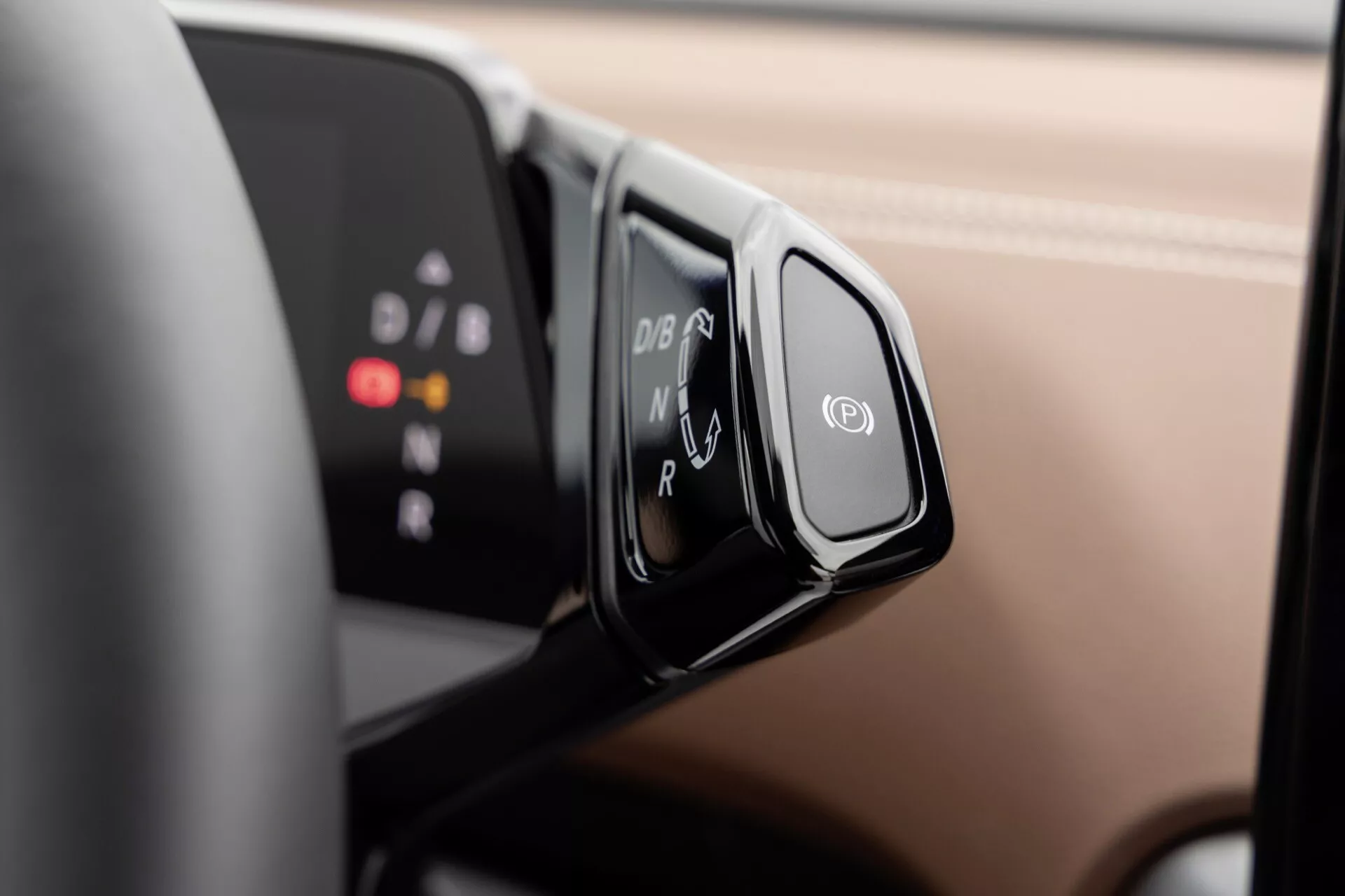 Närbild av VW ID.4 2020-växelväljaren med ergonomisk design och shift-by-wire-system, visar P, R, N, D, B-lägen på svart panel, monterad på styrkolumnen, med suddig digital instrumentdisplay i bakgrunden