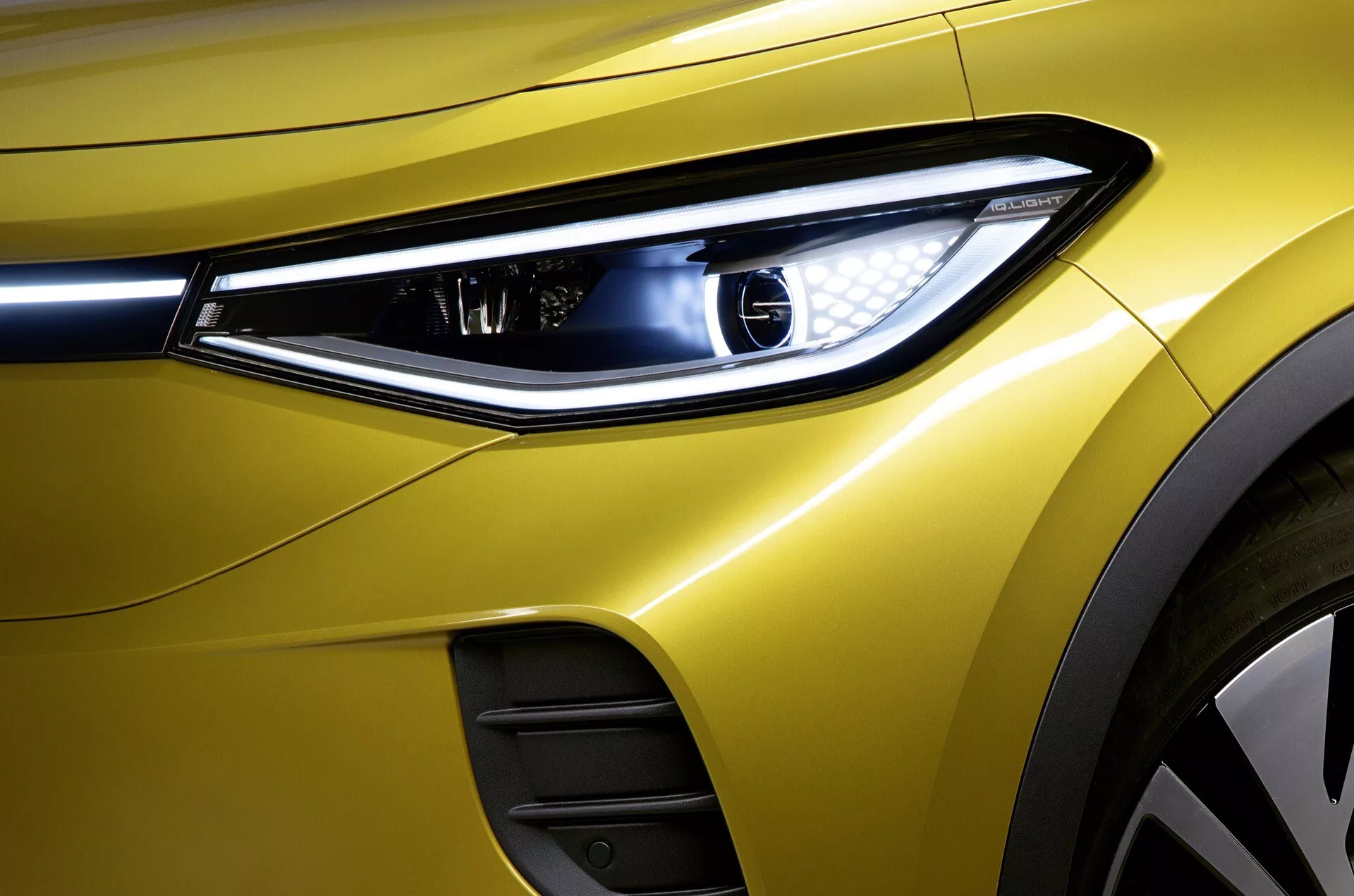 Närbild på 2020 års VW ID.4 som visar dess främre vänstra sektion, med tonvikt på den moderna LED-strålkastardesignen, premium metalliskt gul lack och aerodynamiska karossfunktioner, inklusive en synlig luftventil