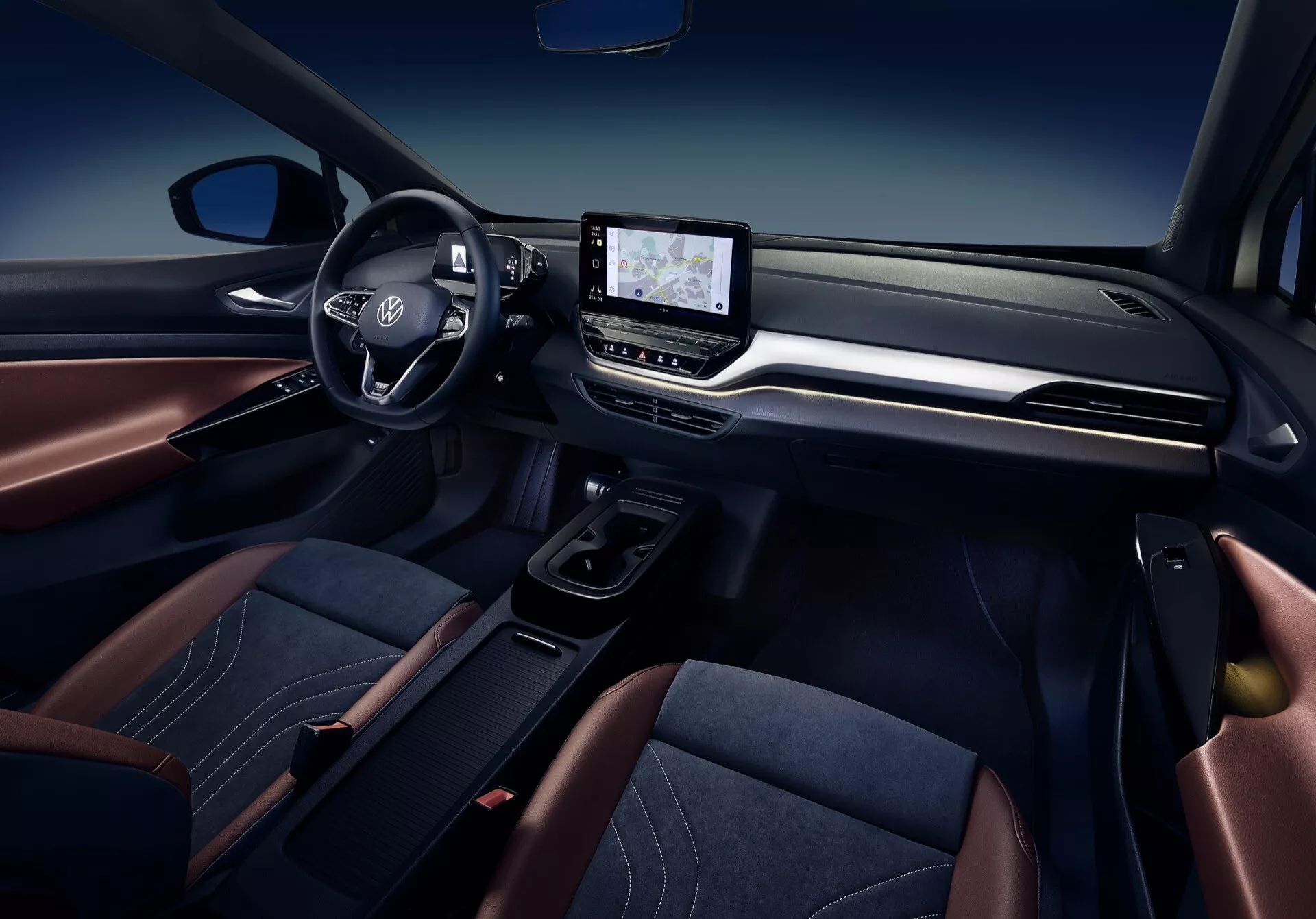 Interiörvy av VW ID.4 1:a generationen 2020 med fokus på instrumentbrädan, ratt med logotyp och monterade kontroller, central infotainment-skärm, gränssnitt för klimatkontroll, elektronisk växelväljare, och premiumklädda säten med kontrastsömmar i en sofistikerad färgsättning