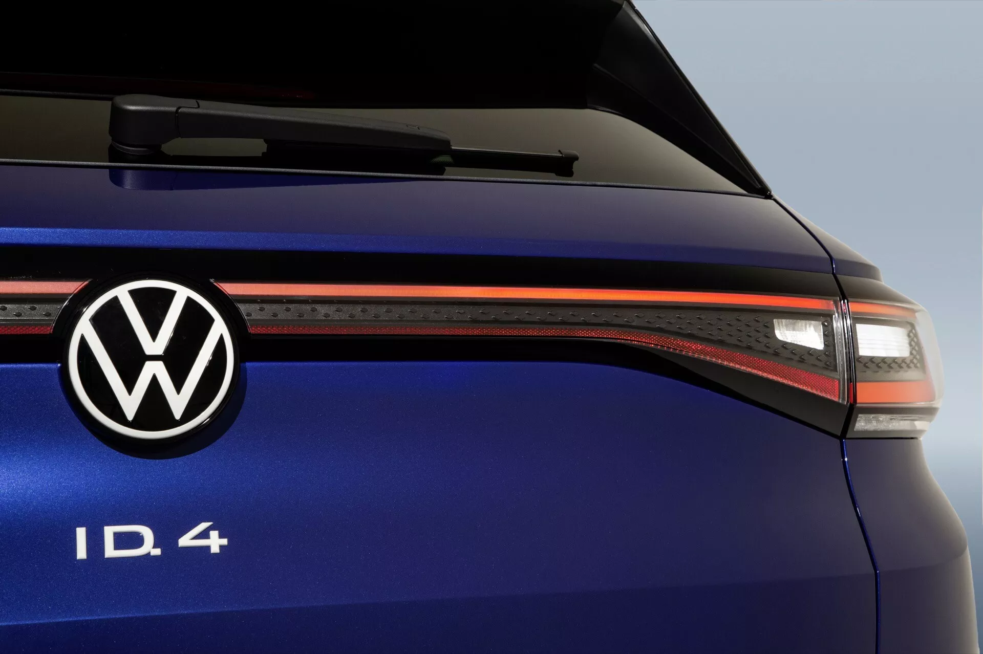 Närbild av bakdelen på Volkswagen ID.4 som visar LED-bakljus, Volkswagen-emblem, modellidentifiering ID.4, metallisk djupblå lack och aerodynamiska designdetaljer