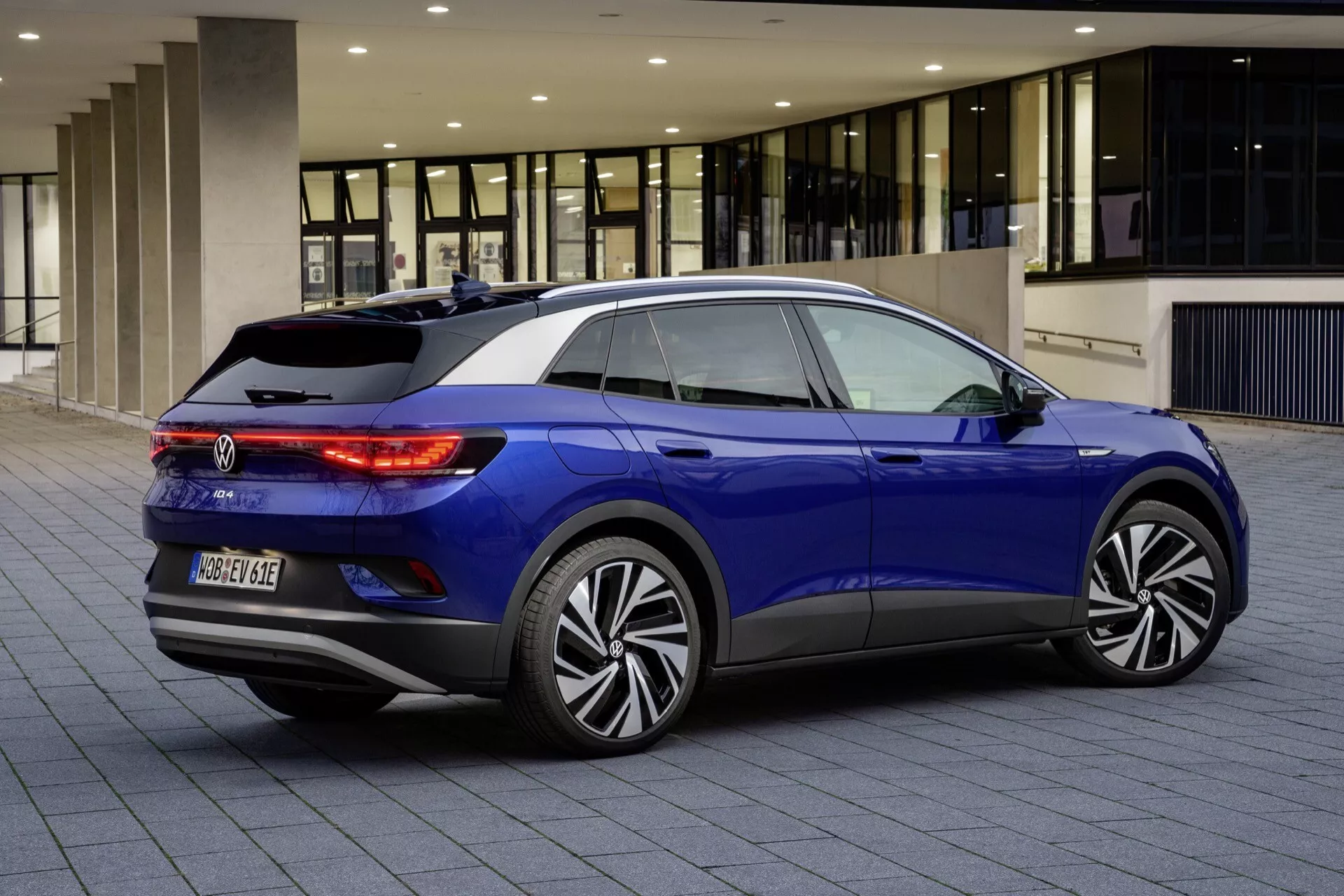 Blå VW ID.4 1:a generationens hatchback, bakifrån tredje kvartalets vy på asfalterad yta, visar LED-baklyktor, modellmärke, flerstråliga legeringshjul, bakre stötfångare med parkeringssensorer, sluttande taklinje med spoiler, bakre vindruta med avfrostare och vindrutetorkare, samt tonade sidorutor.