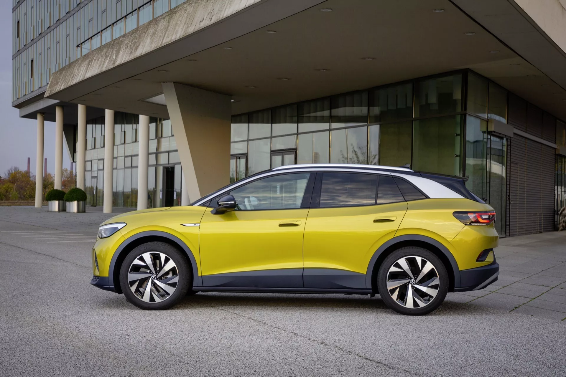 Sidovy av VW ID.4 första generationen 2020 som visar en elegant design, aerodynamisk profil och moderna funktioner som LED-belysning och panoramatak mot en urban bakgrund
