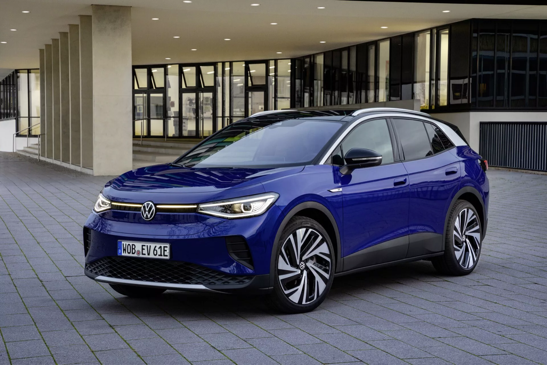 VW ID.4 1:a generationen 2020 i Blått - Modern eldriven hatchback med dynamisk frontgrill, slanka LED-strålkastare med integrerade dagljus, aerodynamisk motorhuv och vindruta design som visar avancerad teknik och stilfulla aluminiumfälgar, fångad från ett tre fjärdedels främre perspektiv i en stadsinställning