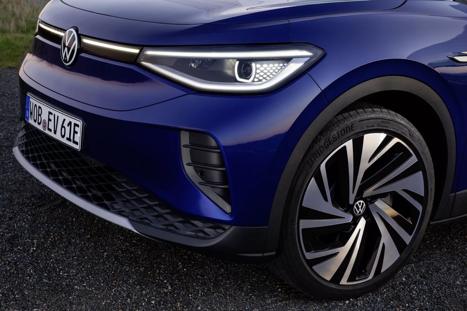 Framifrån kvarts vy av en Volkswagen ID.4 2020 som visar detaljer som det märkta hjulet, LED-strålkastaren, aerodynamiska grillen och metallicblå färgen, framhävande avancerad belysningsteknik, elektrisk fordonsdesign, hjulteknologi och förarassistansfunktioner.