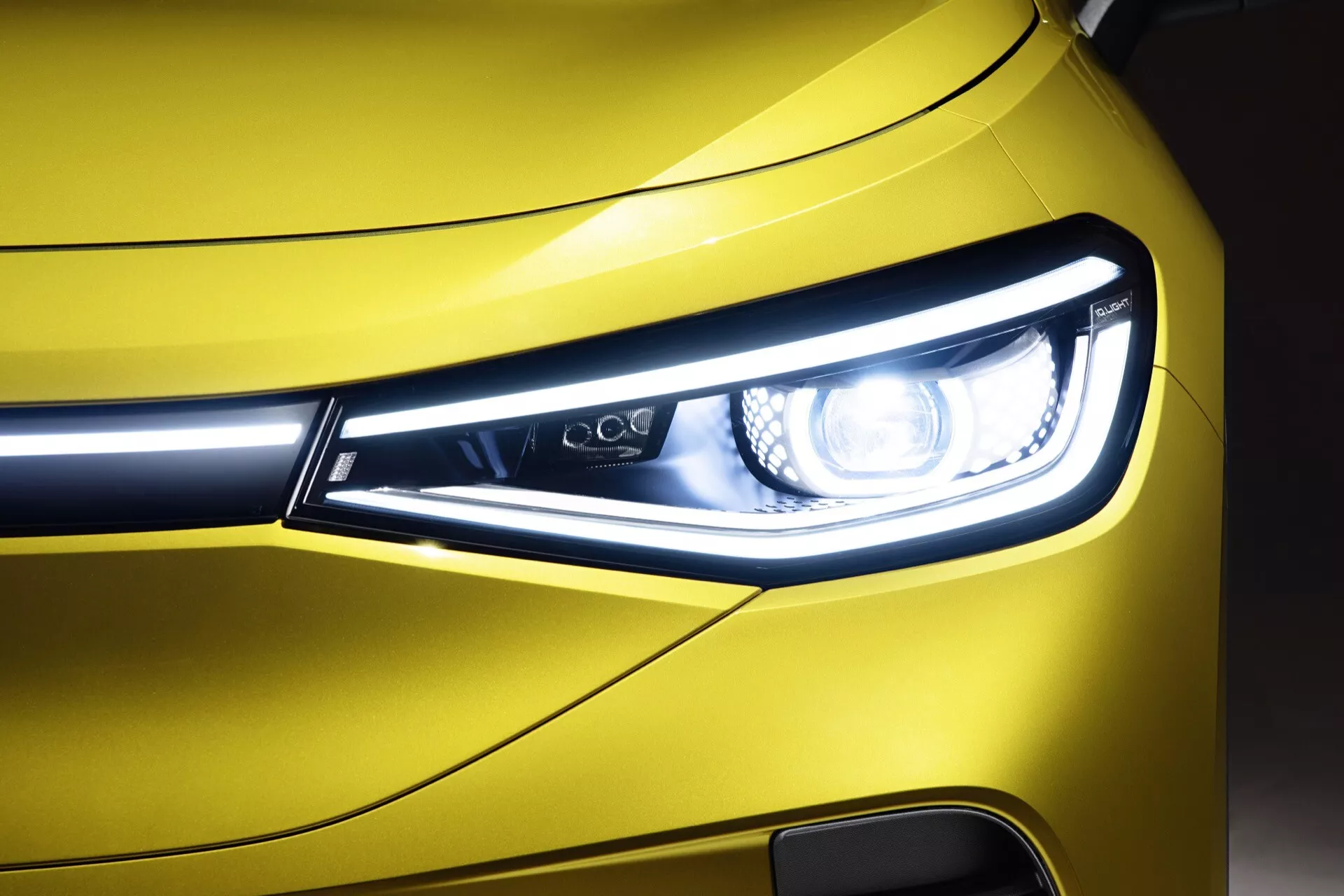 Närbild på en VW ID.4 2020:s främre hörn, som visar LED-strålkastarens design, dagtidsljus och en glimt av den metalliska gula grillen och stötfångaren