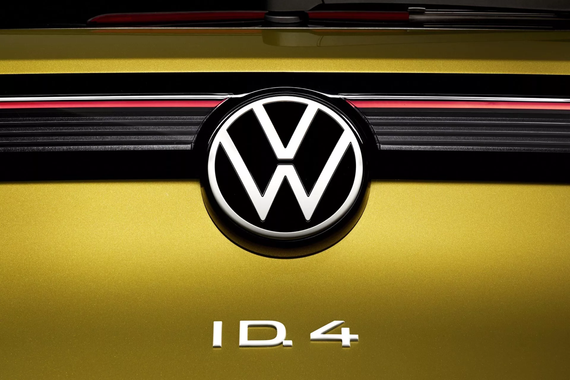 Närbild av baksidan på en Volkswagen ID.4 2020 som framhäver VW-emblemet, modellbeteckningen och designfunktioner inklusive en gyllengul färg och en röd bakljusremsa