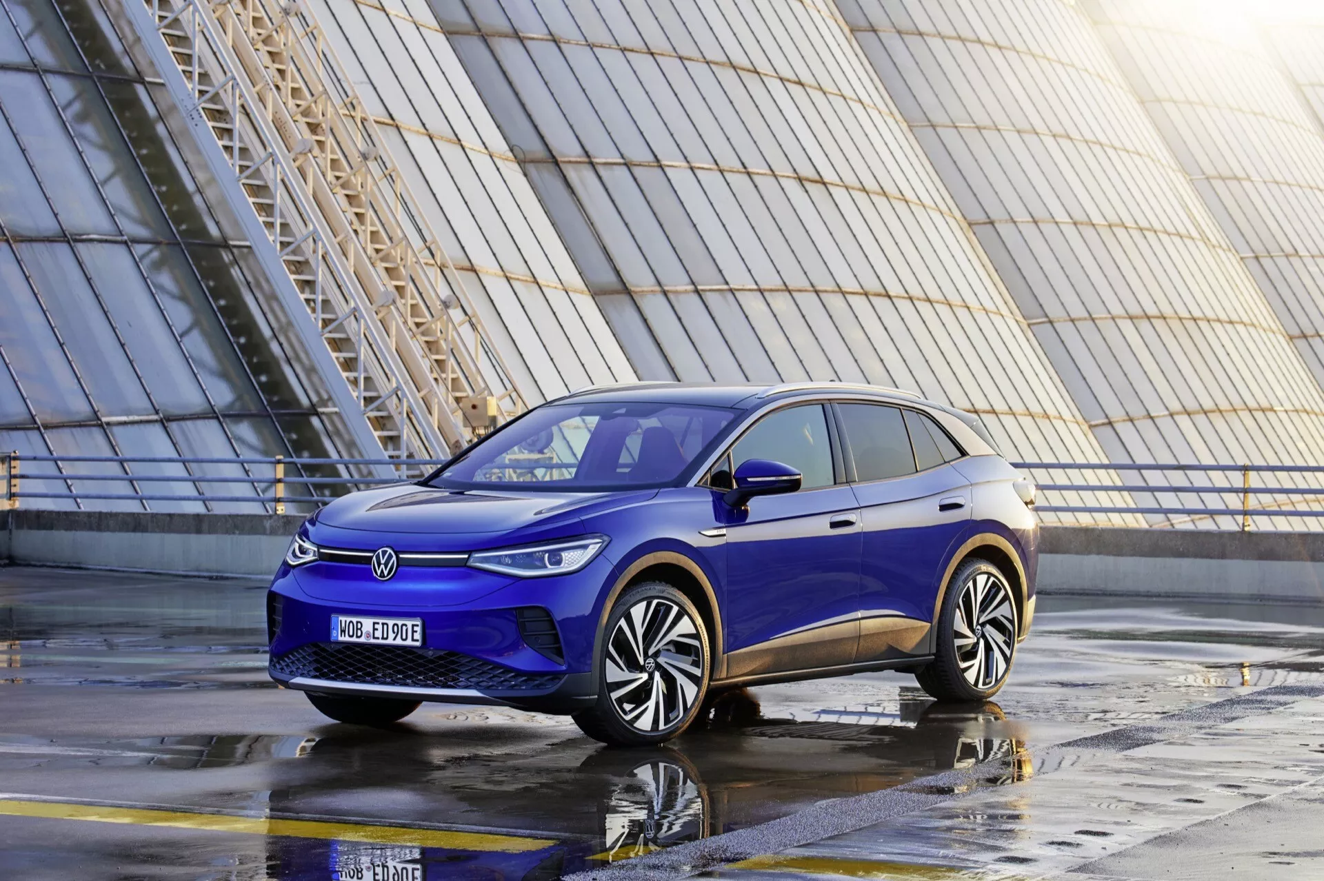 2020 VW ID.4 1:a generationens elektriska SUV i blått, sett från ett lågt framifrån tre kvarts vinkel som framhäver dess LED-strålkastare, stängda frontgrill, aerodynamiska stötfångare och moderna hjuldesign i en stadsinställning