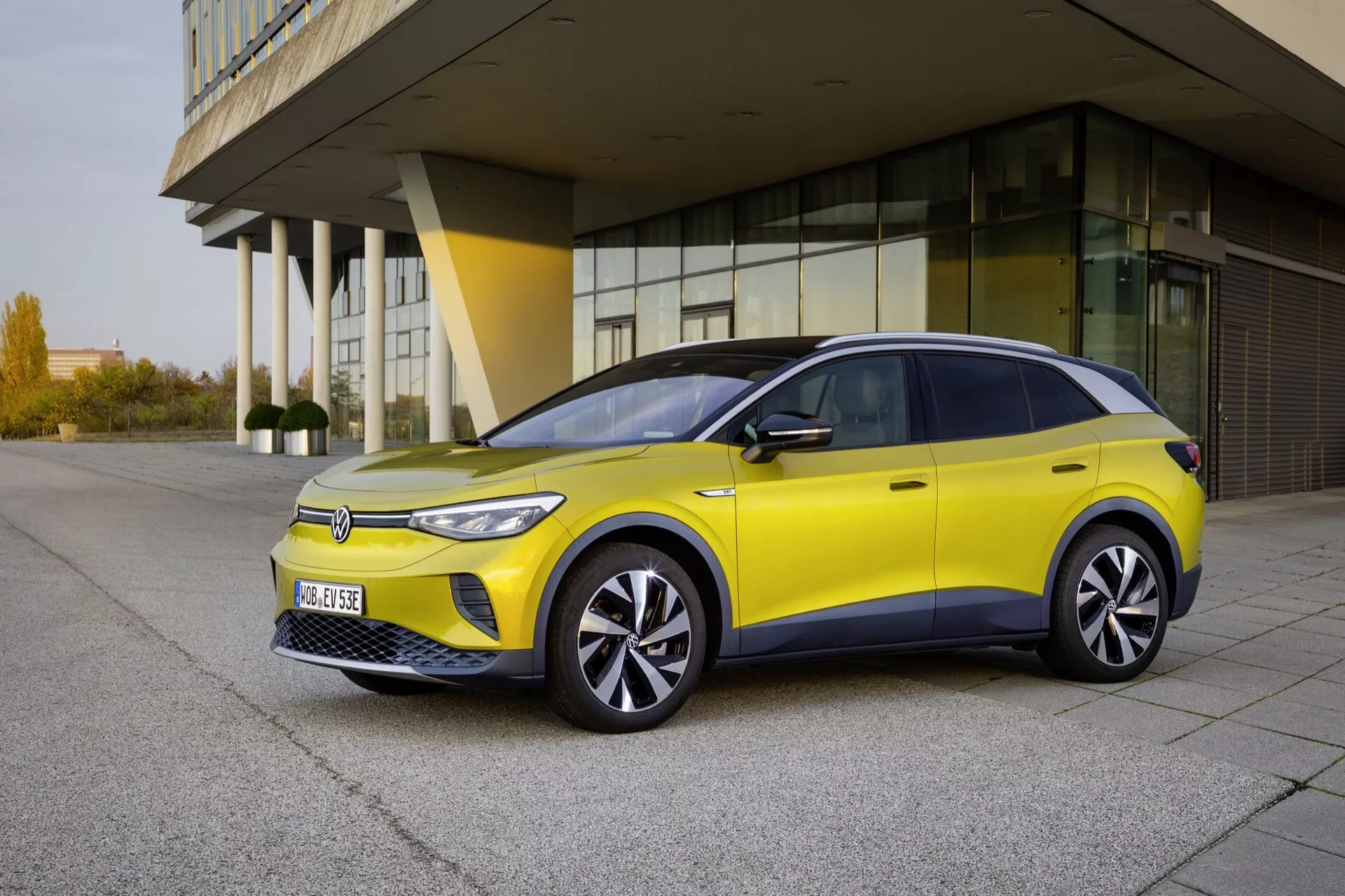 VW ID.4 1:a Generationen 2020 i strålande gult, med LED-strålkastare, aerodynamiska hjul och snygg design fångad från en trekvartsframvy mot modern arkitektur, som belyser dess elektriska, effektiva och miljövänliga egenskaper i dagsljus