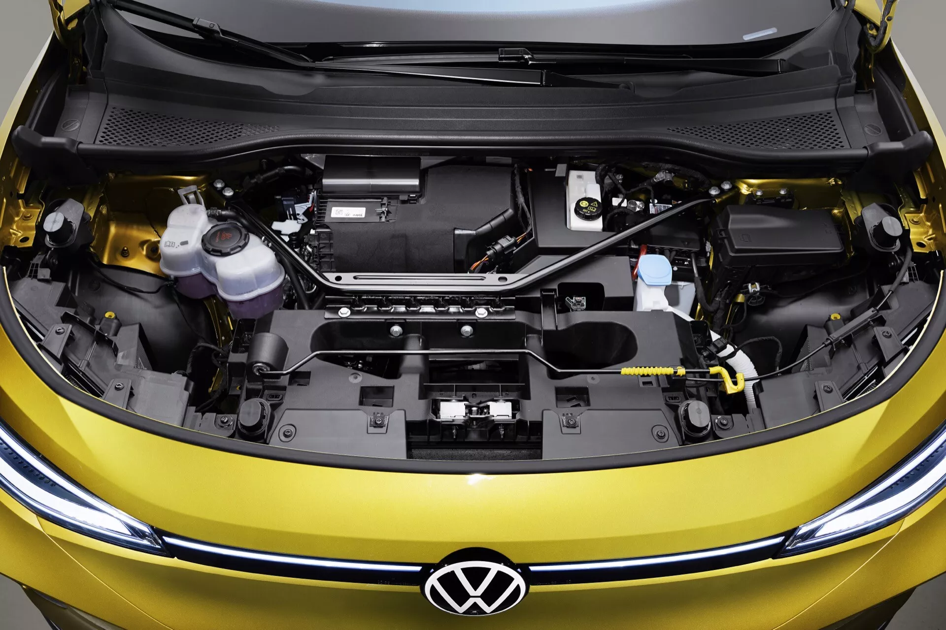 Närbild i hög vinkel på VW ID.4 2020 (1:a generationens) öppna motorutrymme som visar en ren och organiserad layout med Volkswagen-logotyp och motorkomponenter
