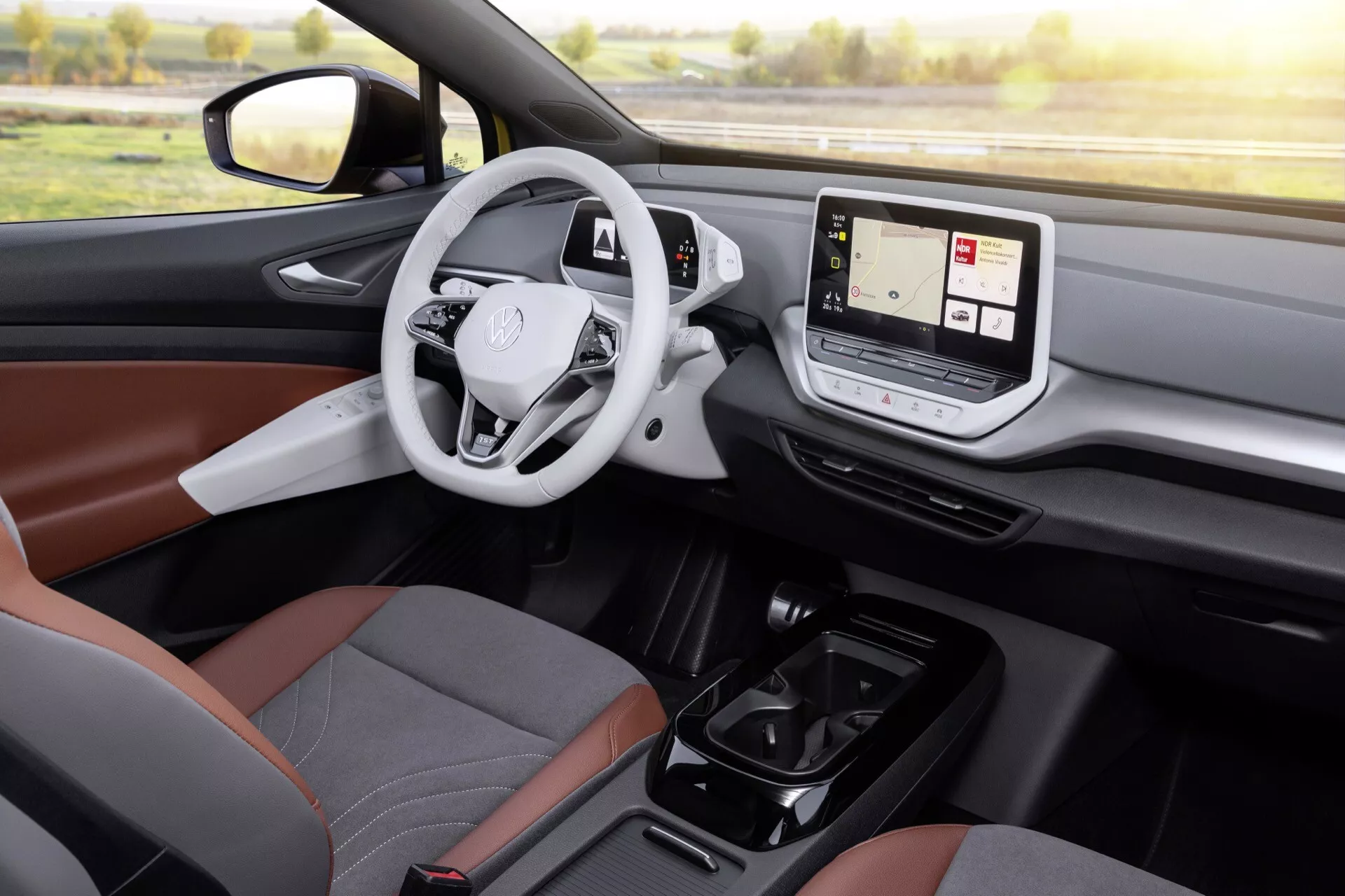 Interiörvy av VW ID.4 2020 Generation 1 med fokus på förarsidan med synligt förarsäte, ratt med emblem, digital instrumentbräda och pekskärmsmittkonsol